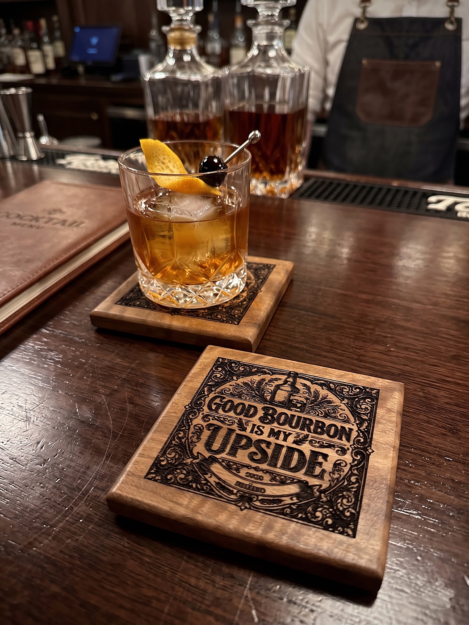 Ipe coasters with corporate branding alongside bourbon
